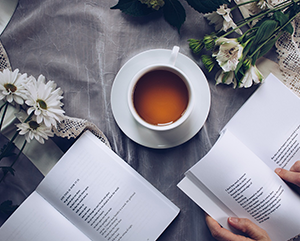 A person drinking tea and reading poetry.