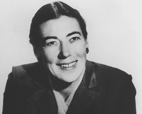 Black and white portrait of a woman with dark hair pulled back, wearing a suit jacket, smiling and looking slightly to the side.