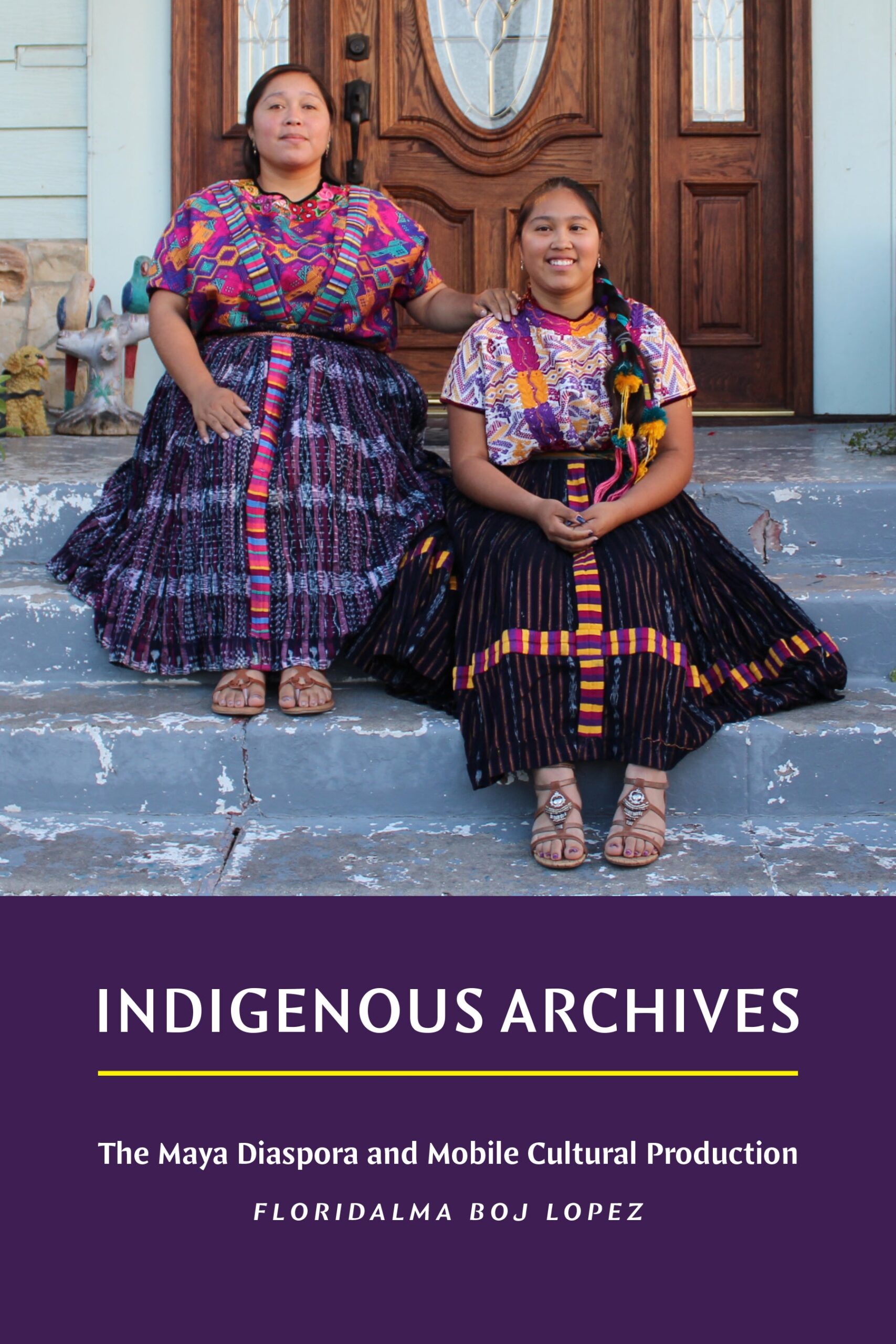 Two women wearing colorful traditional Maya clothing sit on stone steps in front of a wooden door. The book title Indigenous Archives and author Floridalma Boj Lopez are displayed below them.
