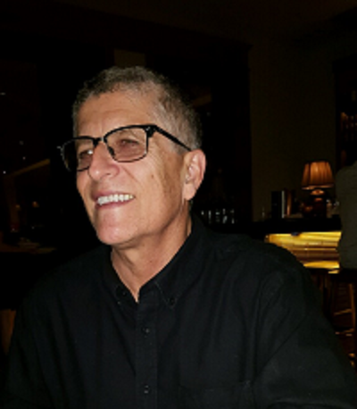 Daniel Gutierrez sitting a low-lit room wearing a black shirt.